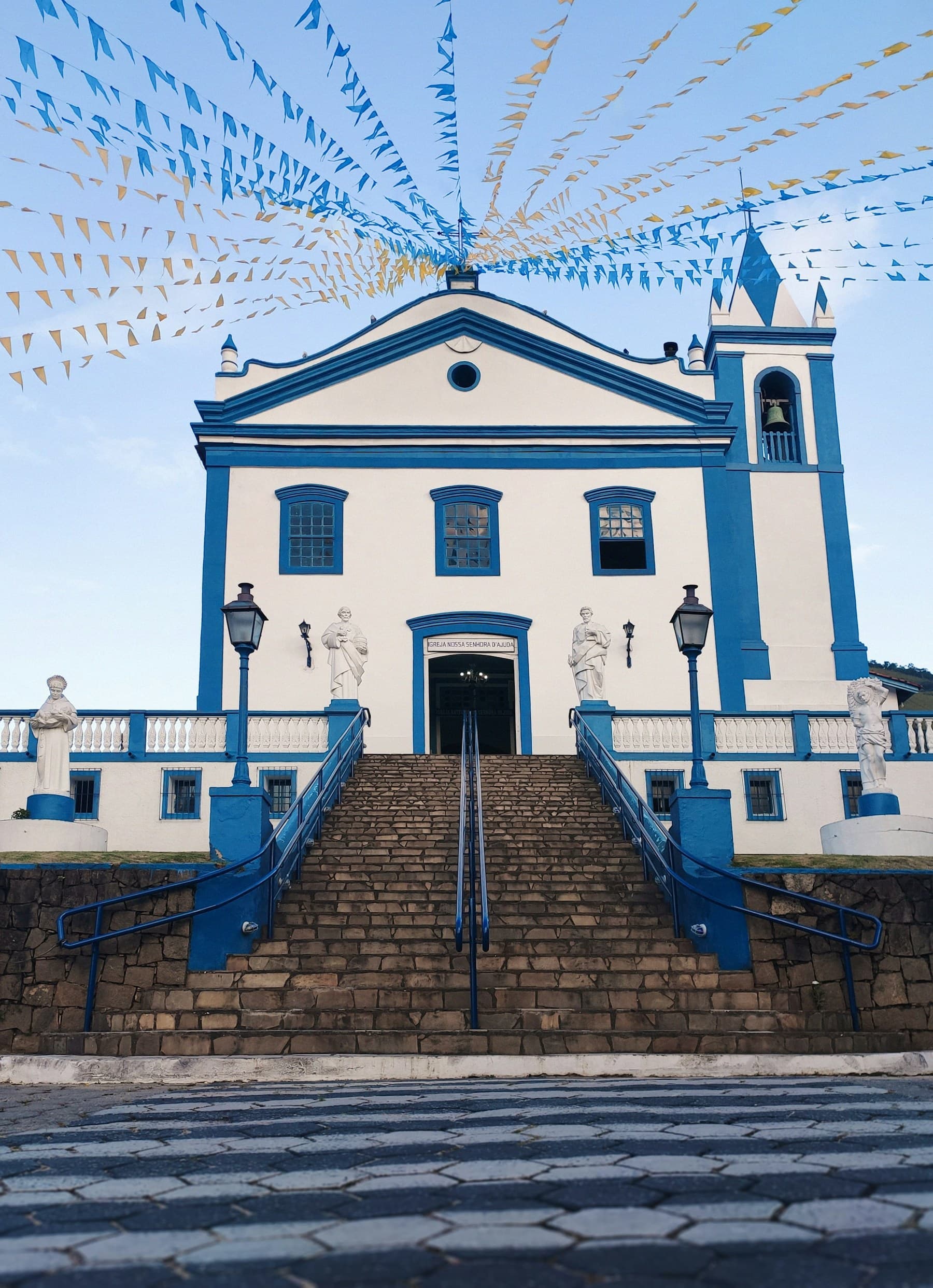Fachada branca de uma pequena igreja com escadaria