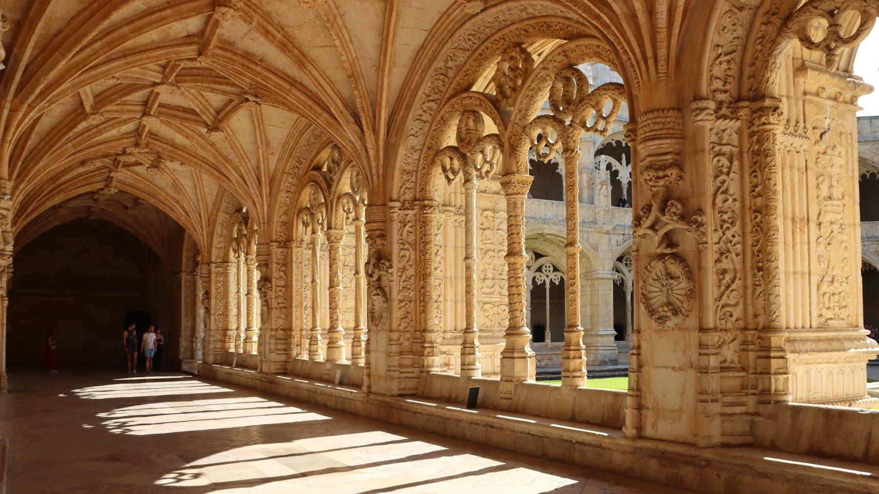 Claustro de pedra com arcos iluminados pelo sol